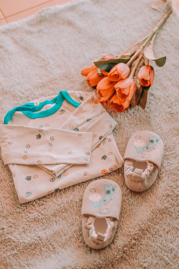 Adorable flat lay of baby clothes with tulips on soft fabric.